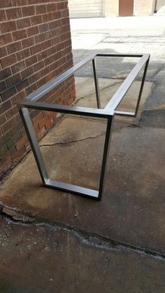 a glass table sitting on the sidewalk next to a brick wall with a window in it