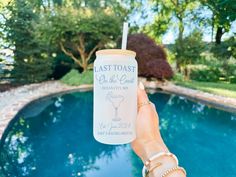 a person holding up a drink in front of a pool with the words last toast on it