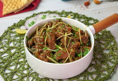 a bowl filled with meat and vegetables on top of a doily next to crackers