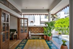 an open porch with potted plants on the side and wooden doors leading to another room