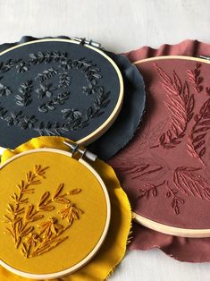 three embroidery designs on different colored plates