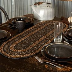 a wooden table topped with black plates and silverware