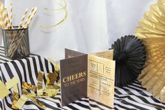 there is a black and white table with gold foil decorations on it, along with paper fans