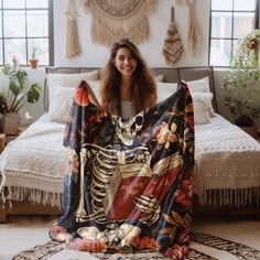 a woman sitting on top of a bed covered in a blanket