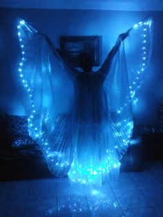 a woman standing in the middle of a room with blue lights on her arms and legs