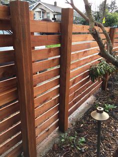 a wooden fence in the middle of a yard with some plants growing on it and a lamp post next to it