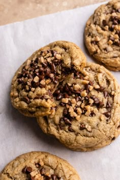 three chocolate chip cookies sitting on top of a piece of paper