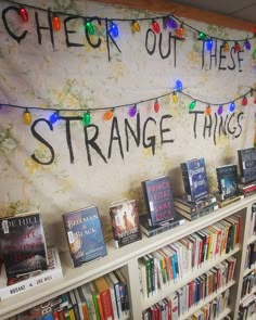 a book shelf filled with lots of books next to a sign that says, check out these strange things