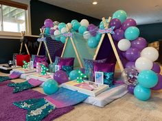 there are balloons and decorations on the floor at this birthday party with purple, teal, and blue colors