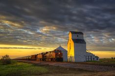 a train traveling past a tall white barn