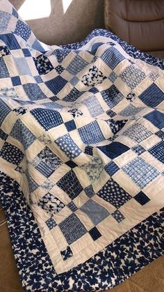 a blue and white quilt sitting on top of a couch