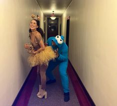 two people dressed as sesame the cat and cookie the dog are walking down a hallway