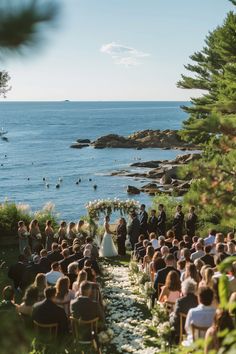 an outdoor wedding ceremony on the beach with water and trees in the backgroud