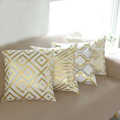 four pillows on a couch in front of a window