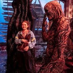 a woman standing next to a giant creature