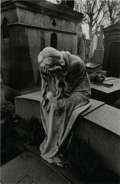 a black and white photo of a woman's head wrapped in a blanket at a cemetery