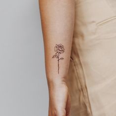 a woman's arm with a single rose tattoo on the left side of her right arm