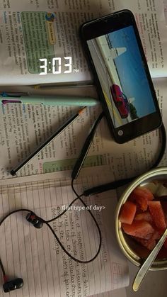 a cell phone sitting on top of a table next to a bowl of strawberries