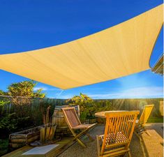 the sun is shining on an outdoor patio with chairs and table under a shade sail