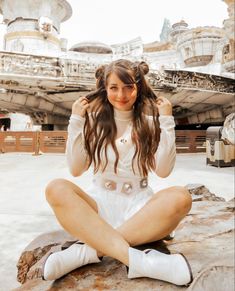 a woman sitting on top of a rock next to a star wars millennium ride in the background