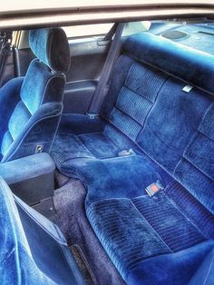 the interior of an old car with blue cloth and black leather upholstered seats