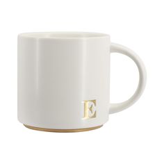 a white coffee cup with gold letters on the inside and outside, sitting in front of a white background