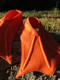 two orange slippers sitting on top of a tree stump