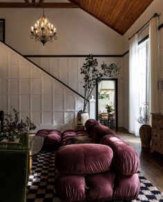 a living room filled with lots of furniture and a chandelier hanging from the ceiling