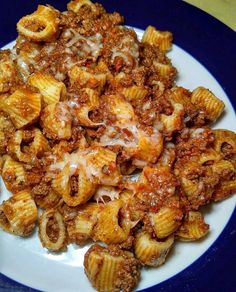 a blue and white plate topped with pasta covered in sauce, cheese and other toppings