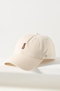 a white baseball cap with a red dog embroidered on the front and side, sitting on a white surface