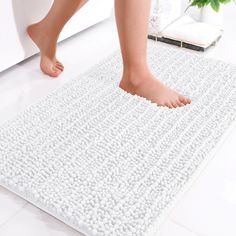 a person standing on top of a white rug next to a bathtub and toilet