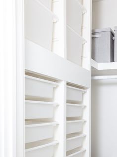 an empty closet with white shelving and bins on the shelves next to each other