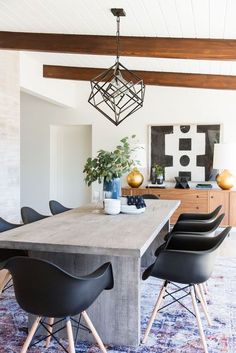 a dining room table with black chairs and a rug on the floor in front of it