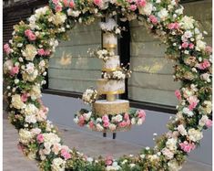 a wedding cake is surrounded by flowers in front of a store window with the word love spelled on it