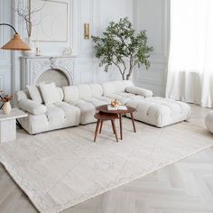 a living room with white furniture and a large rug