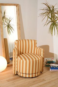 an orange and white striped chair sitting in front of a mirror on top of a hard wood floor