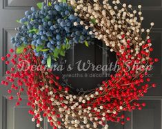 a wreath with red, white and blue berries hanging on the front door for christmas