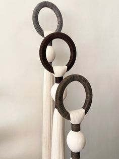 an artistic sculpture made out of wood and white yarn, hanging on a wall next to a curtain