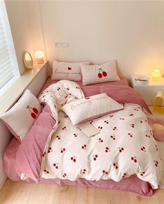 a bed with white and pink sheets, pillows and fruit decorations on the comforter