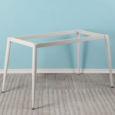 a white table sitting on top of a hard wood floor next to a blue wall