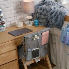 a laptop computer sitting on top of a wooden desk next to a bed covered in blankets