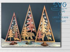 three wooden christmas trees with snowflakes and stars on them, in front of a blue background