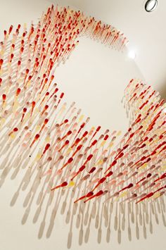 an art installation made out of toothpicks on the wall in a room with white walls