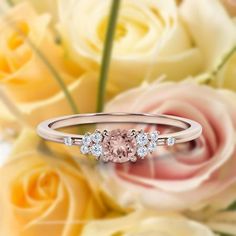 a pink diamond ring sitting on top of flowers