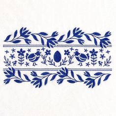 a blue and white embroidered design with leaves, flowers, and an egg on it