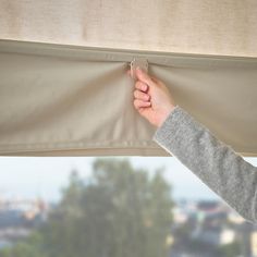 a person is pulling the curtain off of a window with their hand and thumb on it