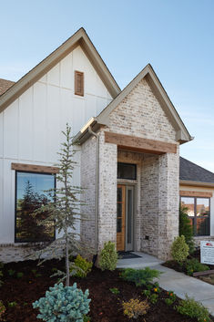 a brick and stone home with landscaping in front of the door, windows and bushes