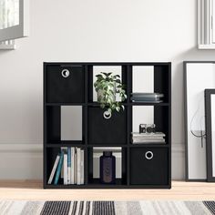 a book shelf with several cubes and some plants in it next to a window