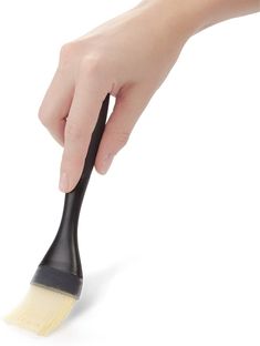 a hand holding a black and white brush with yellow bristles on it's tip