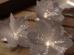 two white flower lights are sitting on a wooden table